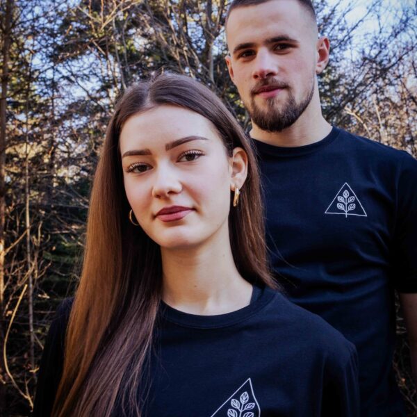 Modelpaar trägt schwarzes Unisex T-Shirt mit weißem Pflanzenmotiv und Dreieck