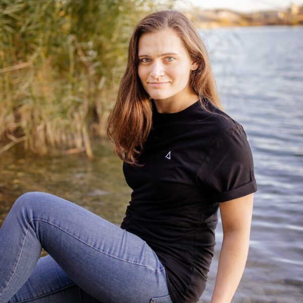 Weibliches Model trägt schwarzes Unisex T-Shirt mit weißem Karlmotte Dreieck