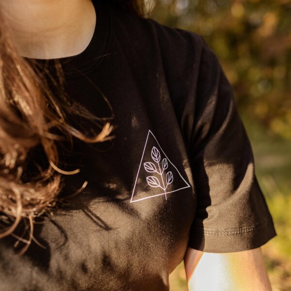 Nahaufnahme schwarzes Unisex T-Shirt mit weißem Pflanzenmotiv und Dreieck