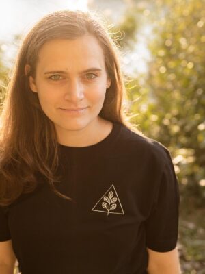 Weibliches Model trägt schwarzes Unisex T-Shirt mit weißem Pflanzenmotiv und Dreieck