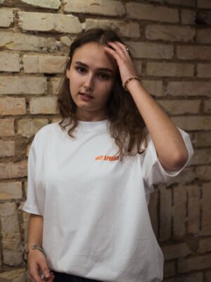 Ganzkörperaufnahme in weißem Box Tee Shirt mit orangenen HOLY APEROLY Wortzug