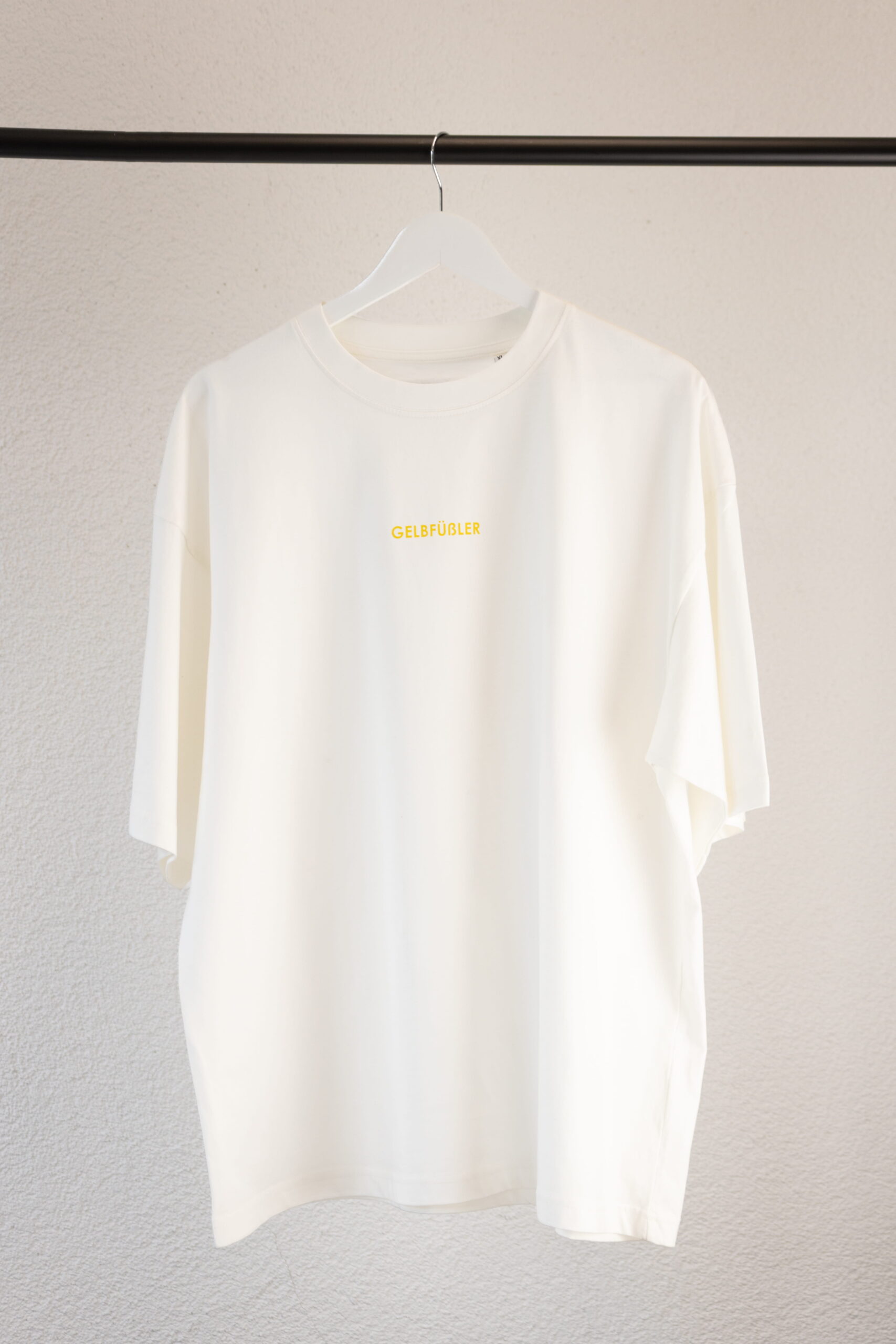 Ganzkörperaufnahme in weißem Box Tee Shirt mit gelbem Gelbfüßler Wortzug