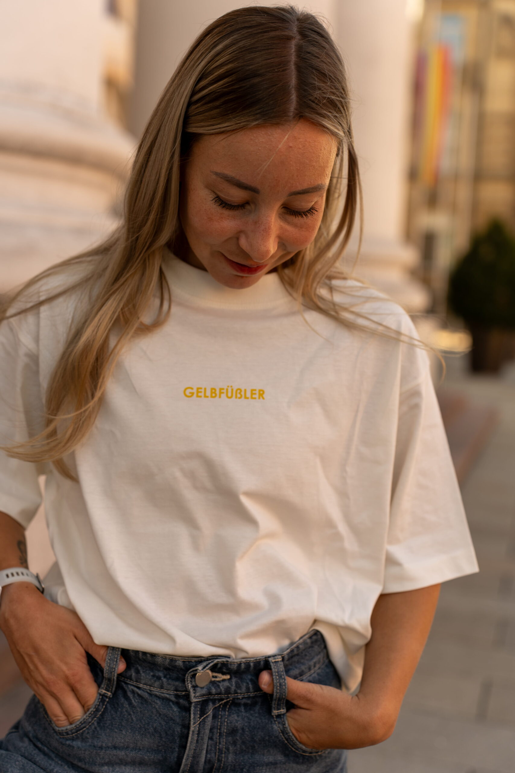Ganzkörperaufnahme in weißem Box Tee Shirt mit gelbem Gelbfüßler Wortzug